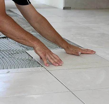Close-up of hands carefully laying ceramic tiles during flooring installation.