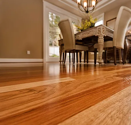 Elegant dining room showcasing newly refinished hardwood floor with warm tones and natural lighting.