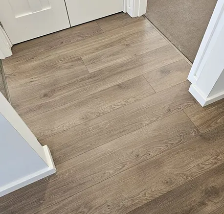 Light gray laminate flooring installed in a home entryway with white walls and natural light