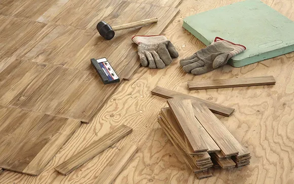Wood flooring repair tools and wooden planks scattered on the floor for Livonia MI floor repair service.