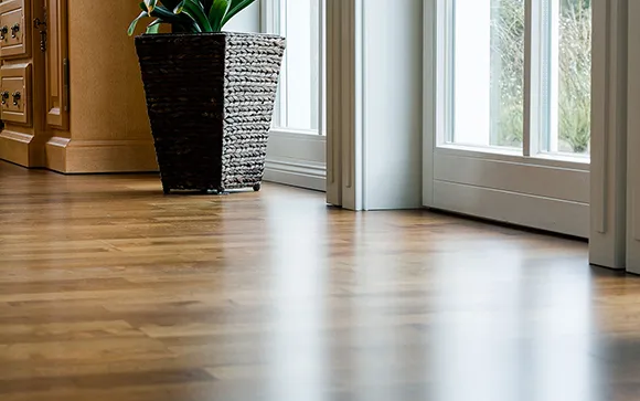Light oak hardwood floor in a bright room with large windows and modern decor.