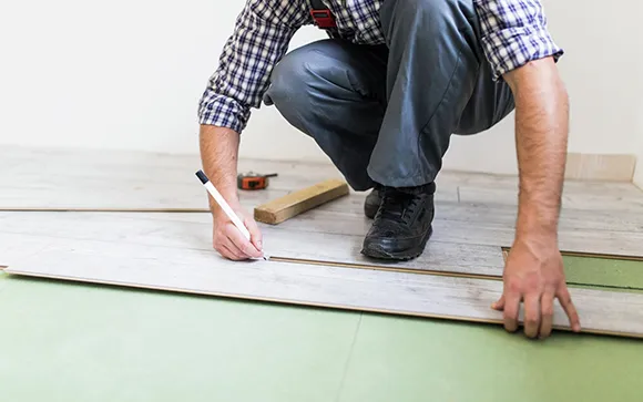 Professional laying luxury vinyl plank flooring in a residential room.