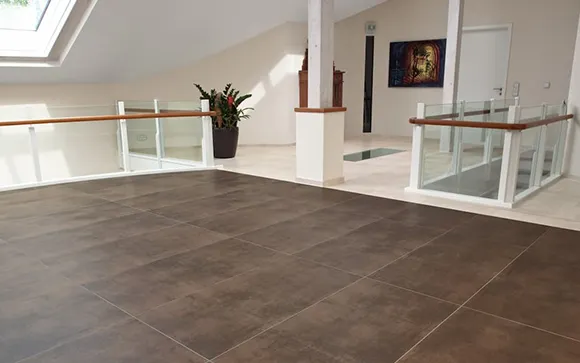 Spacious home entryway with large ceramic tile flooring, staircase, and minimalist decor.