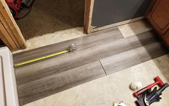 Close-up of damaged floor area with measuring tape for emergency floor repair in Rochester Hills MI.