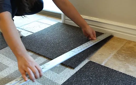 Person measuring and leveling floor surface with ruler before carpet laying in Livonia MI.
