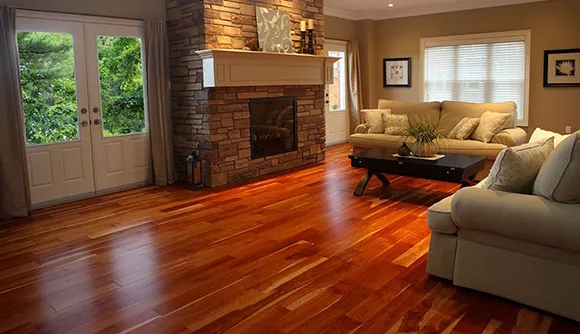 Inviting living room featuring glossy laminate wood flooring and a stone fireplace.