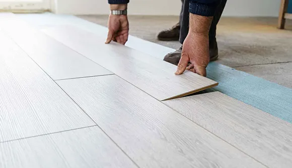 Close-up of hands wiping and maintaining white luxury vinyl plank flooring surface.