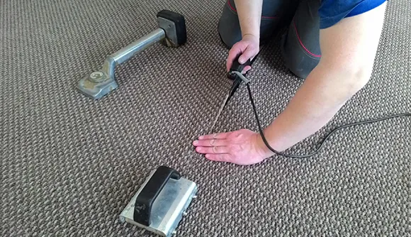 Close-up of professional cleaning carpet using a handheld carpet vacuum tool.