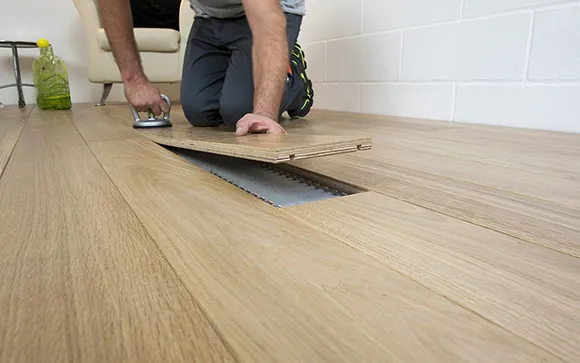 Flooring professional installing luxury vinyl plank flooring inside a home.