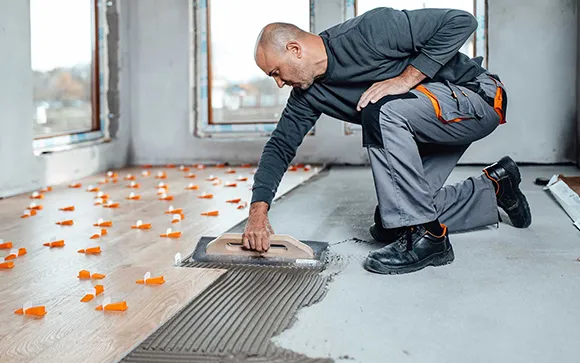 Professional tile contractor applying adhesive and setting ceramic tile in Rochester Hills MI.