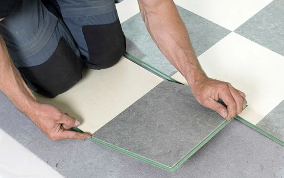 Installer measuring and marking ceramic tile for precise cutting in Madison Heights MI.