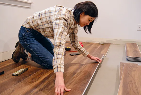 Professional installing laminate flooring by fitting planks on the floor in a home setting.